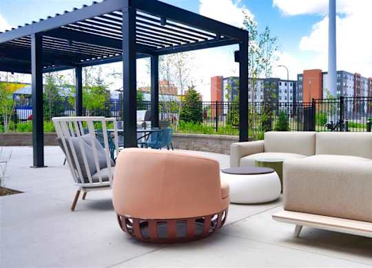 A patio with a white chair and a white couch at The Bessemer at Seward Commons Apartments, Minneapolis, 55404