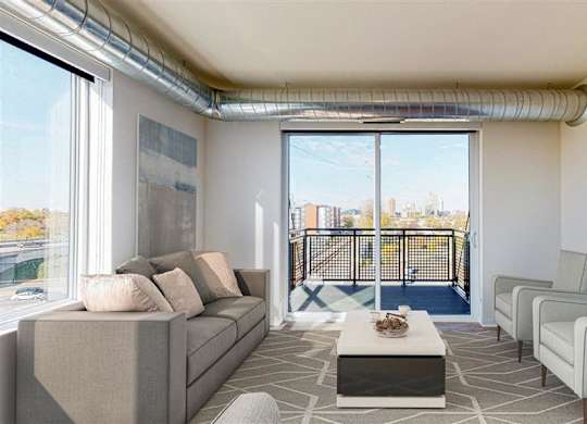 A living room with a couch, chairs, and a coffee table at The Bessemer at Seward Commons Apartments, Minnesota, 55404