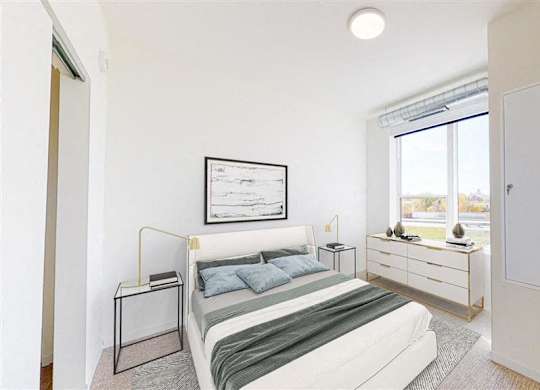 A bedroom with a bed, nightstand, and a window with blinds at The Bessemer at Seward Commons Apartments, Minneapolis, Minnesota
