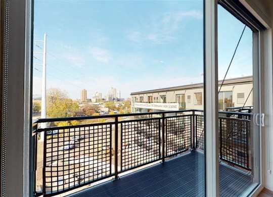 A balcony with a black railing and a view of a cityscape at The Bessemer at Seward Commons Apartments, Minneapolis, 55404
