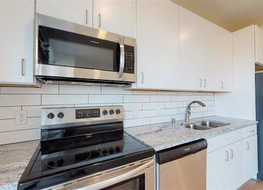 A kitchen with a stove, microwave at The Bessemer at Seward Commons Apartments, Minneapolis, Minnesota