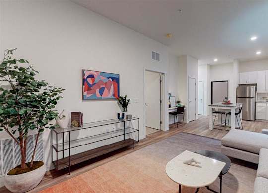 A living room with a grey couch, a coffee table, and a painting on the wall at The Bessemer at Seward Commons Apartments, MN, 55404