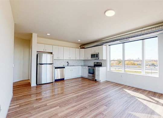 A spacious kitchen with white cabinets and a wooden floor at The Bessemer at Seward Commons Apartments, Minneapolis