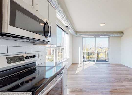 A kitchen with a black stove top oven at The Bessemer at Seward Commons Apartments, MN, 55404