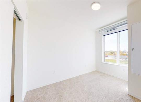 A room with a window and a carpet on the floor at The Bessemer at Seward Commons Apartments, Minnesota