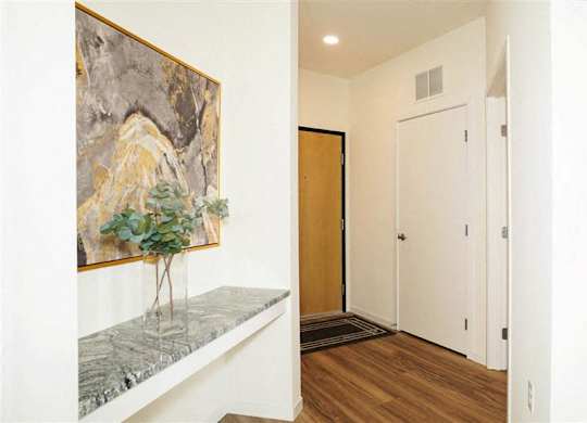 A hallway with a painting on the wall and a bench with a tree on it at The Bessemer at Seward Commons Apartments, Minneapolis, Minnesota