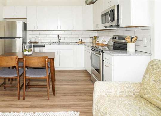 A kitchen with a table and chairs in the middle of the room at The Bessemer at Seward Commons Apartments, Minnesota