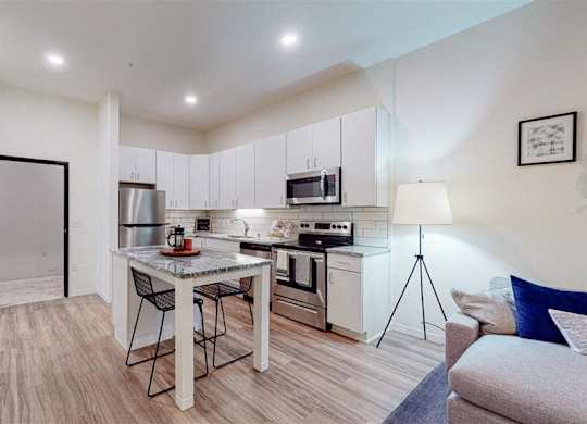 A modern kitchen with a dining table and chairs at The Bessemer at Seward Commons Apartments, Minneapolis, Minnesota