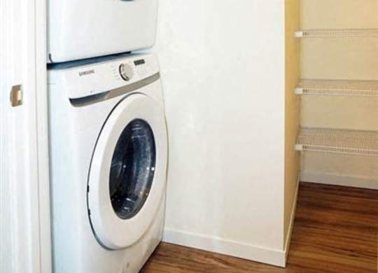 A white washing machine and dryer in a small laundry room at The Bessemer at Seward Commons Apartments, Minneapolis, 55404