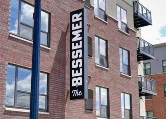 A street lamp stands in front of a building with the word at The Bessemer at Seward Commons Apartments, Minneapolis