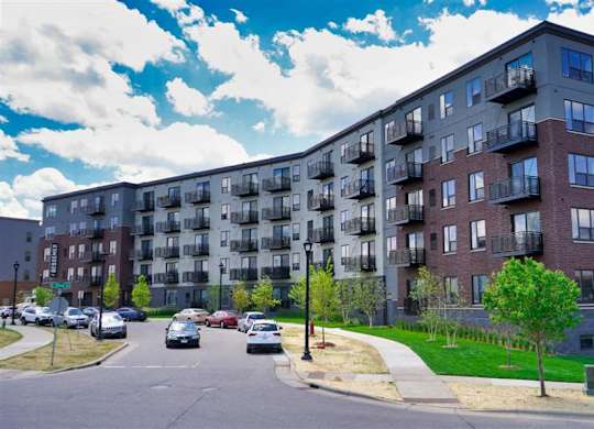 A large apartment building with a parking lot in front at The Bessemer at Seward Commons Apartments, Minneapolis, 55404