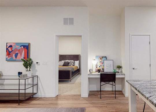 A modern living room with a bed, desk, and chair at The Bessemer at Seward Commons Apartments, Minneapolis