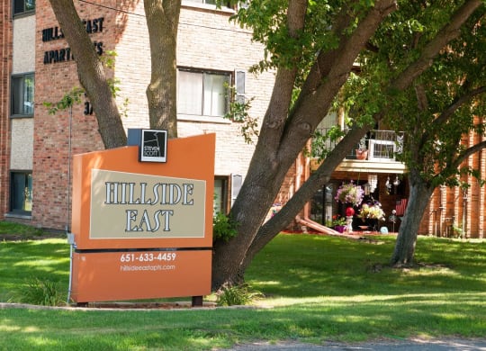 a sign that says hillside east in front of a brick building
