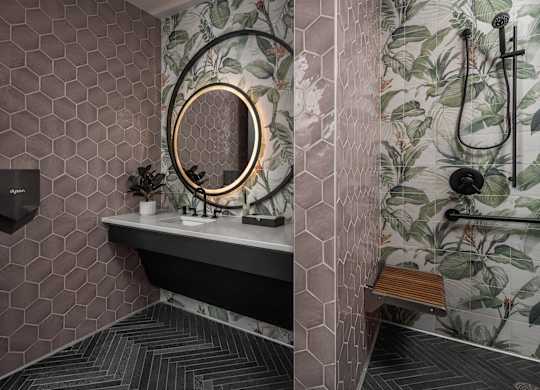 A bathroom with a hexagonal tile wall and a round mirror.