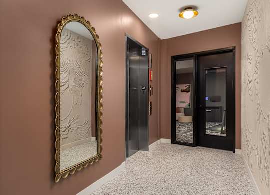 A hallway with a large mirror and a wall with a carving.