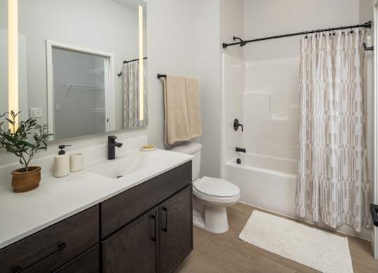 A bathroom with a white toilet, sink, and shower.