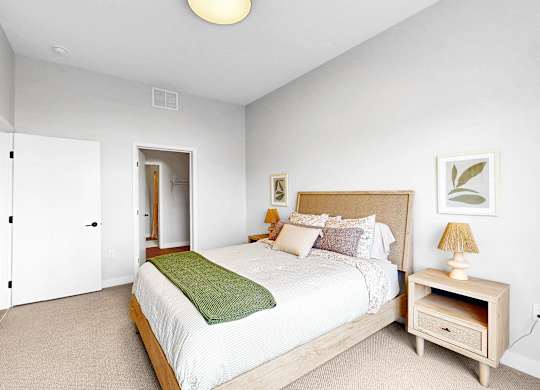 A bedroom with a bed, nightstand, and lamp.