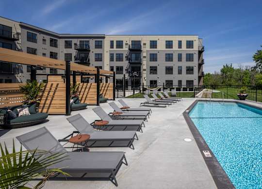 A swimming pool surrounded by lounge chairs and a building in the background.