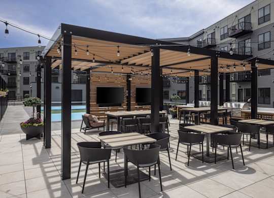 A patio with tables and chairs and a pool in the background.