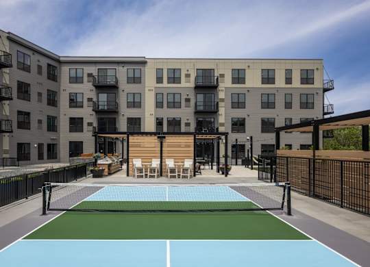 A tennis court is located in the courtyard of a modern apartment building.