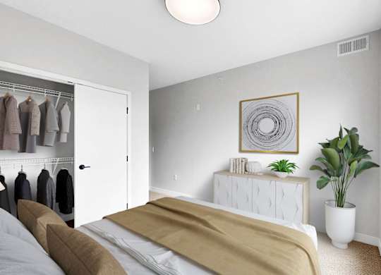 A bedroom with a bed, a plant, and a wardrobe.