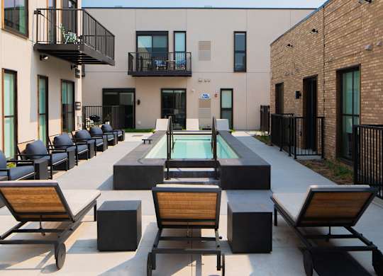 A modern outdoor seating area with a pool table and lounge chairs.