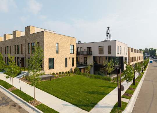 A row of modern houses with a grassy front yard.