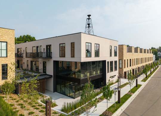 A modern building with a glass facade and a metal structure on top.