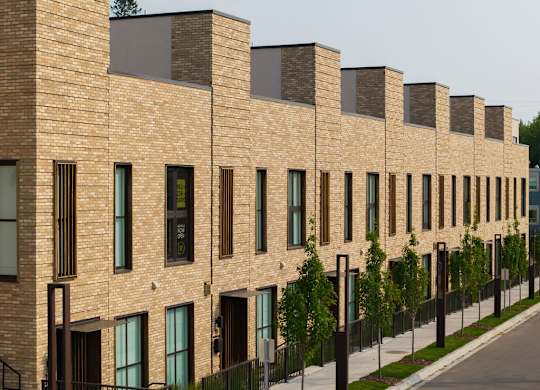 A long row of brown brick houses with black railings.