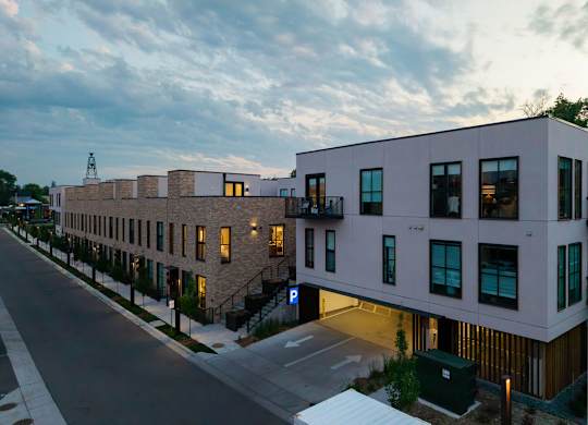A modern building with a flat roof and a parking lot in front.