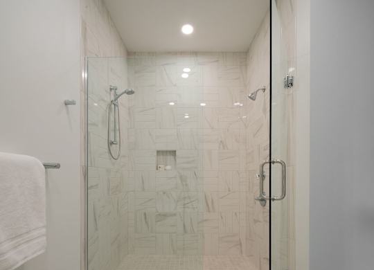 A white tiled shower with a glass door.