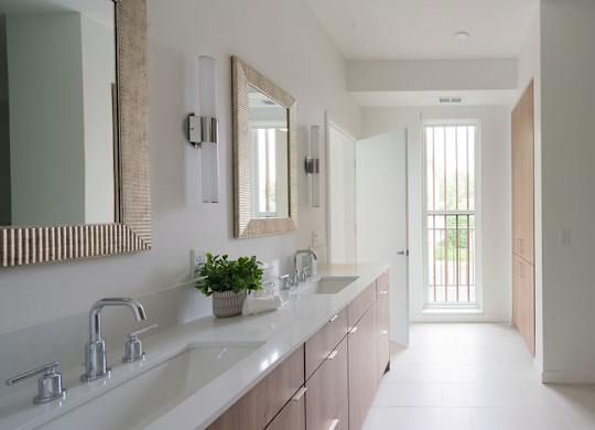 A modern bathroom with a long counter and a large mirror.