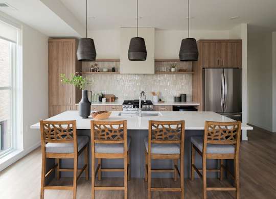 A kitchen with a white countertop and wooden chairs.