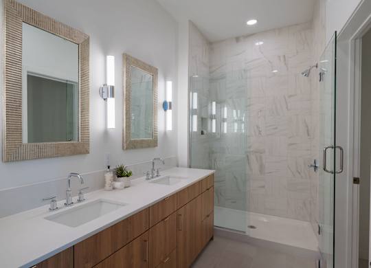 A bathroom with a marble wall and a glass shower.