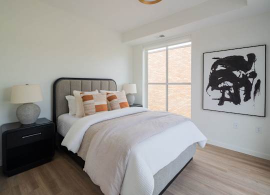 A bedroom with a large bed and a painting on the wall.