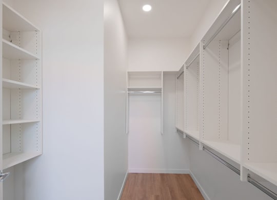A long hallway with white walls and shelves on the side.