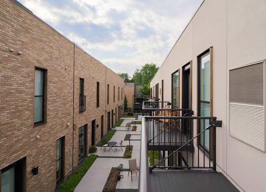 A long building with a balcony and a table and chairs on it.