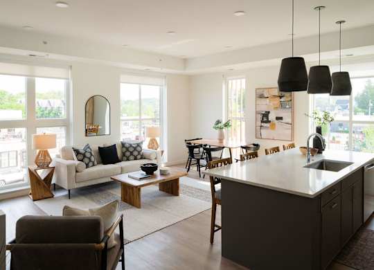 A modern kitchen and living room with a large island and lots of natural light.