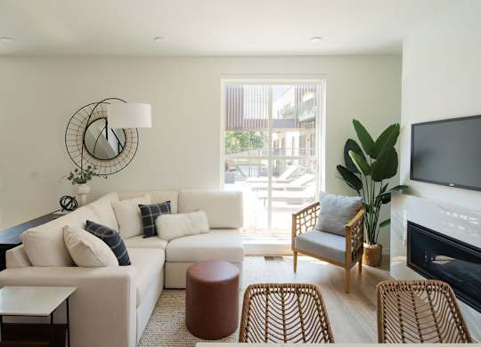 A living room with a white couch, a chair, a table, and a television.