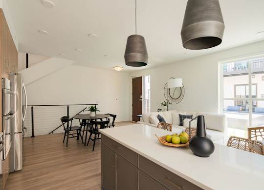 A modern kitchen with a white countertop and a bowl of fruit on it.