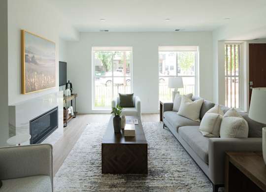 A living room with a grey couch and a fireplace.