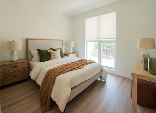 A bedroom with a large bed and two lamps.