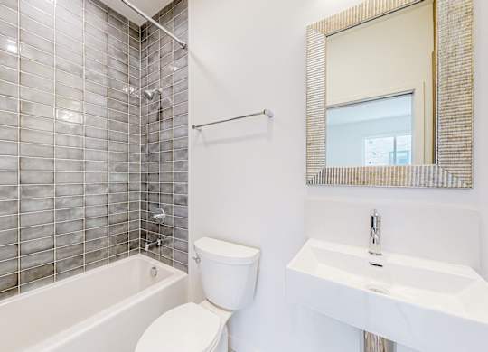 A white toilet sits next to a white sink in a bathroom with a glass block wall at One West Drive Apartments, Excelsior, MN 55331
