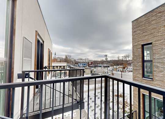 A balcony with a black railing and a view of a snowy landscape at One West Drive Apartments, Excelsior, 55331