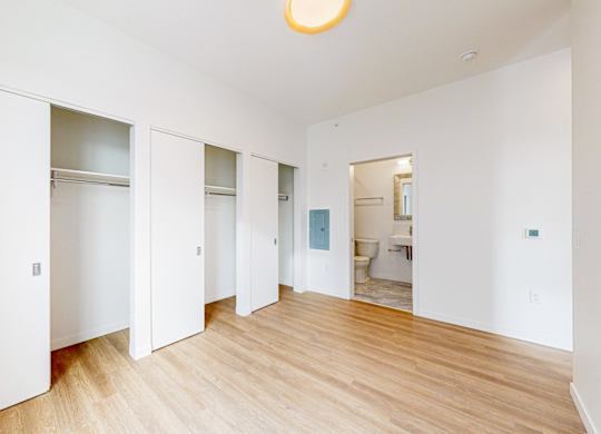 A white room with a wooden floor and a round light on the ceiling at One West Drive Apartments, Minnesota