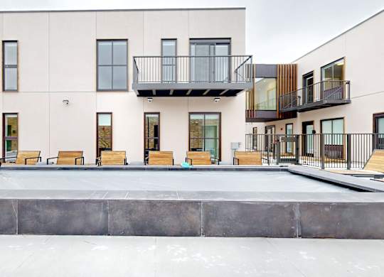 A modern building with a balcony and a pool in front.