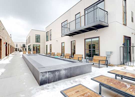A snow-covered walkway leads to a building with a balcony.