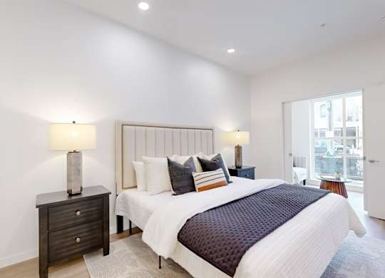 A bedroom with a large bed and a nightstand with a lamp.