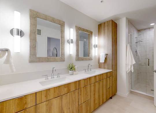 A bathroom with a wooden vanity and a mirror above it.