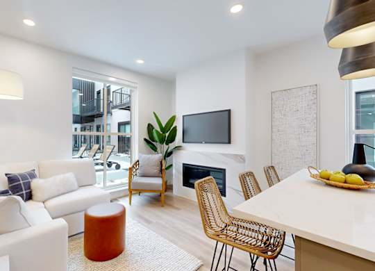 A modern living room with a white sofa, a wooden coffee table, and a TV mounted on the wall.